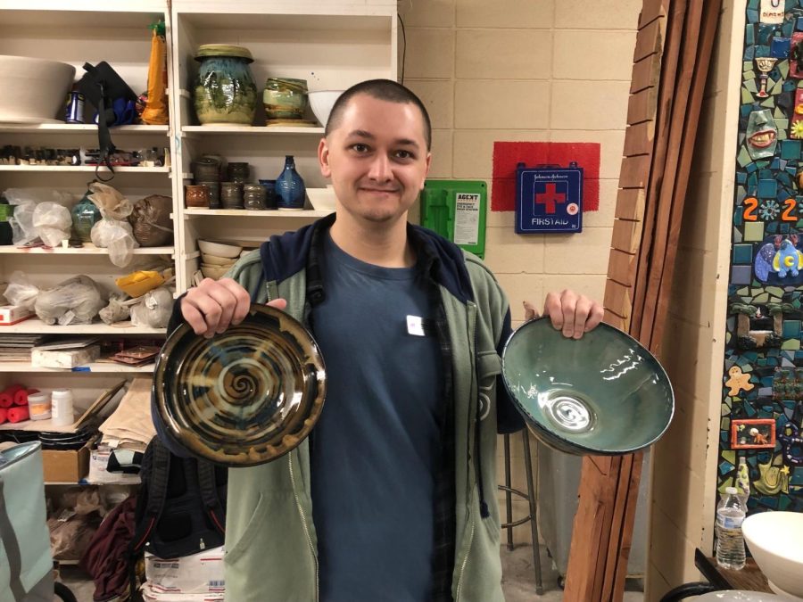 The classs teaching assistant, Brandon Cagle, smiles as he shows the bowls made during class.