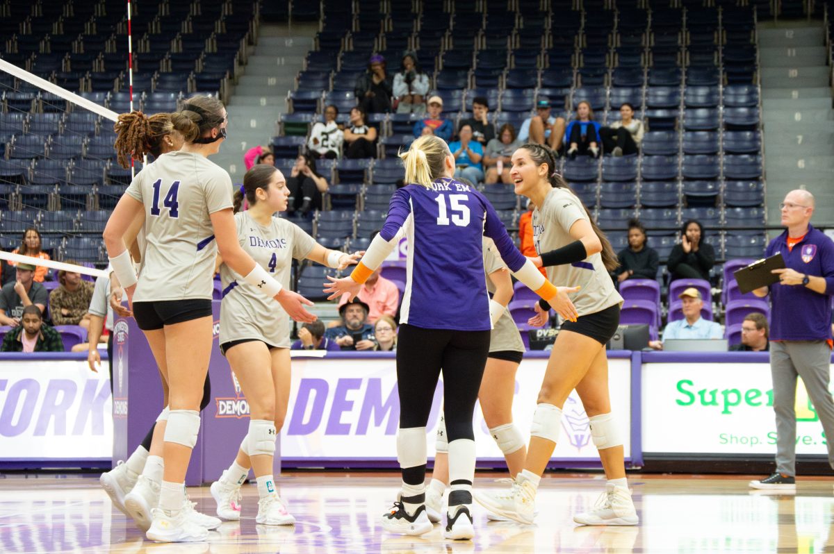 Lady Demons celebrate after rally against the Houston Christian University Huskies.