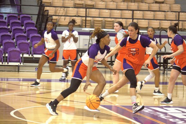 Nia Hardison, senior general studies major and point guard, dribbles to the hoop against teammates in practice. 