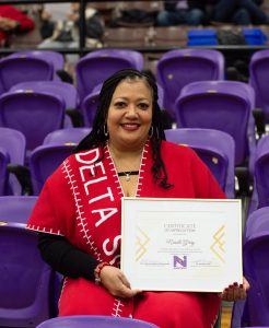 Nicole Gray sits in the audience for a Demons basketball game during which she was honored.