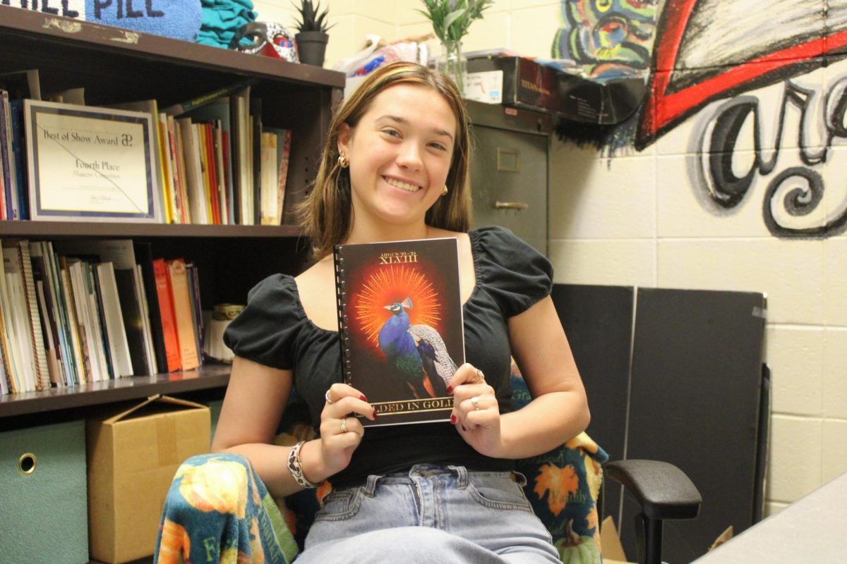 Rebecca Scott, the Editor-in-Chief for Argus, poses with last year's book, "Gilded in Gold."